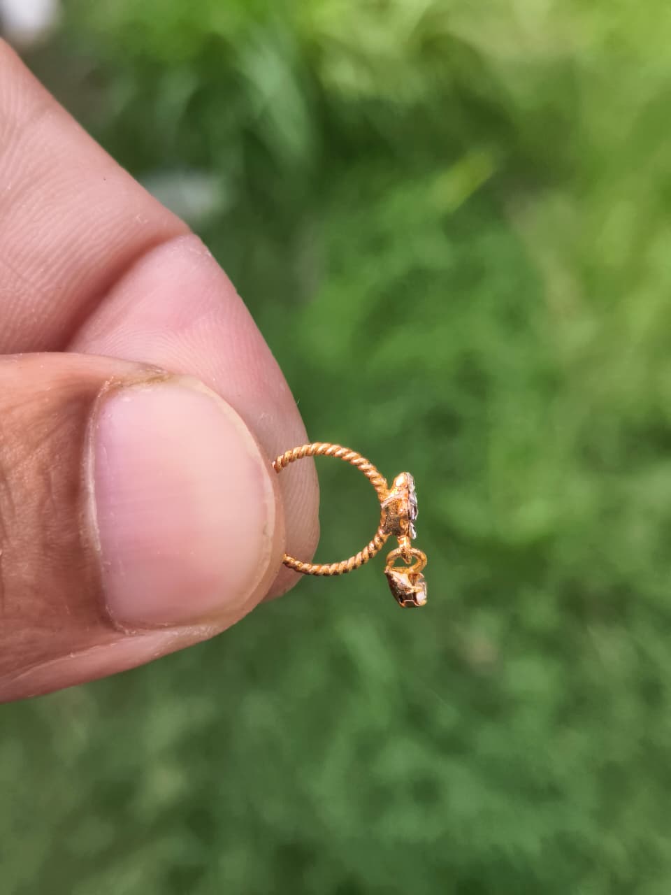 Gold ring with a small object on a blurred green background
