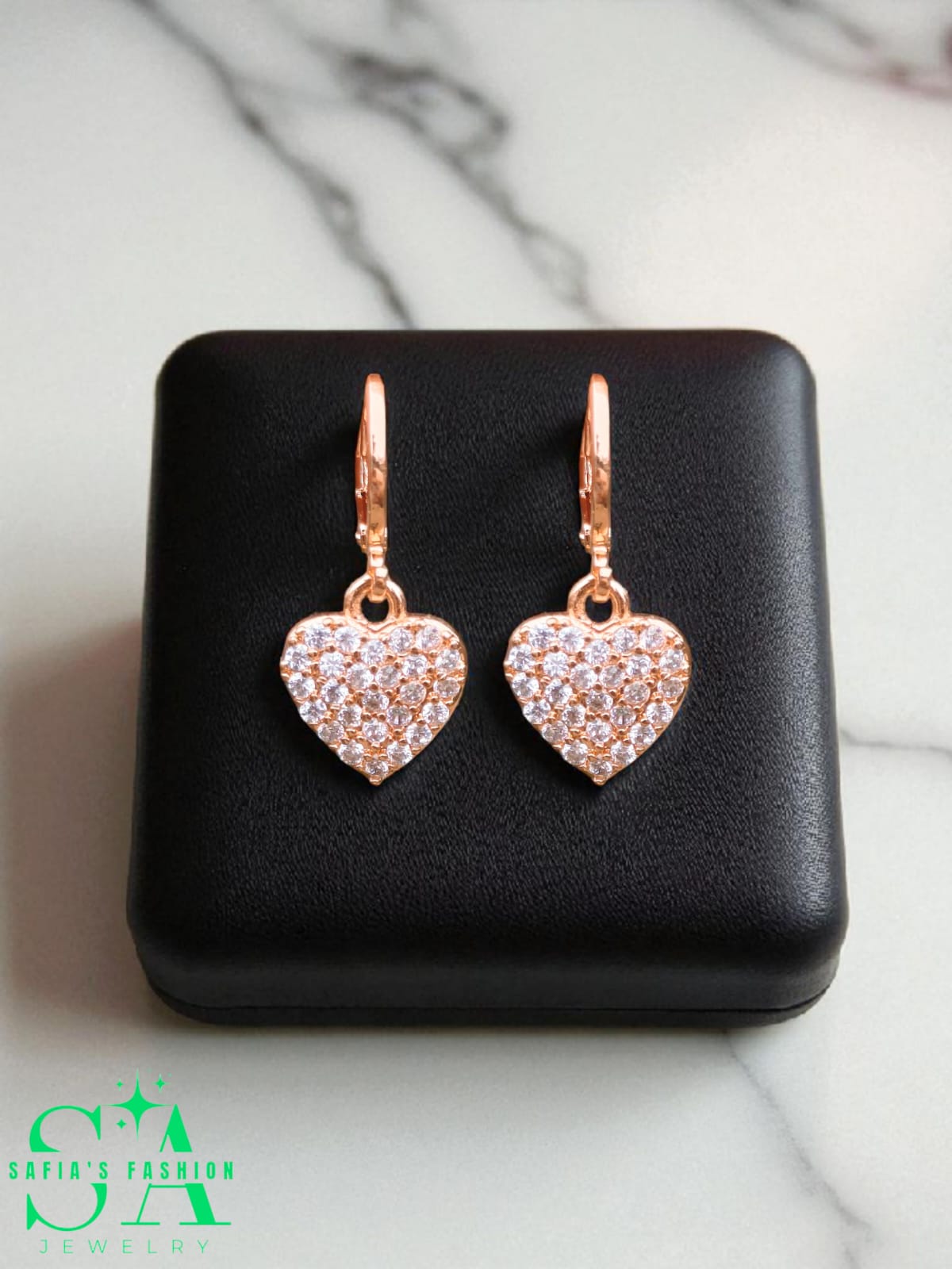 Heart-shaped earrings with rose gold finish and clear stones on a black jewelry box.