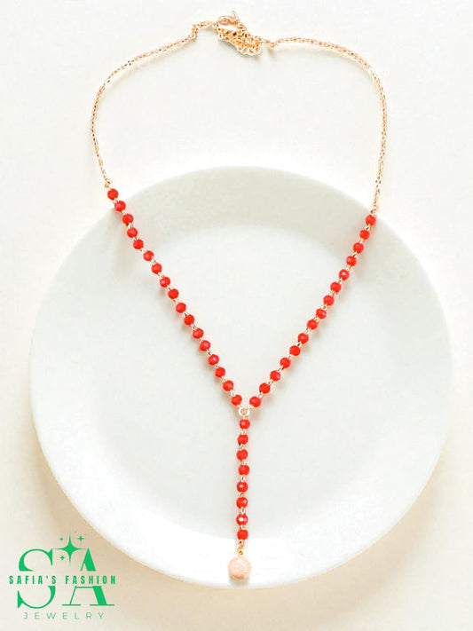 Red beaded necklace on a white plate with 'Safia's Fashion' logo.