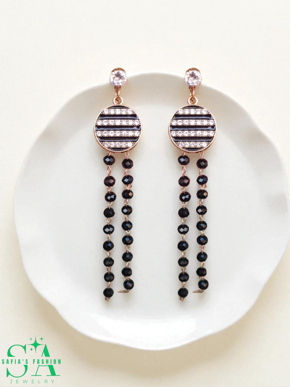 Pair of black beaded earrings with rose gold accents on a white plate, branded 'SA'.
Long Drop Earrings with Black Pearls – Elegant Jewelry for Women

Close-up of Black Pearl Drop Earrings – Stylish Party Wear

Woman Wearing Black Pearl Long Earrings – Fashion Jewelry