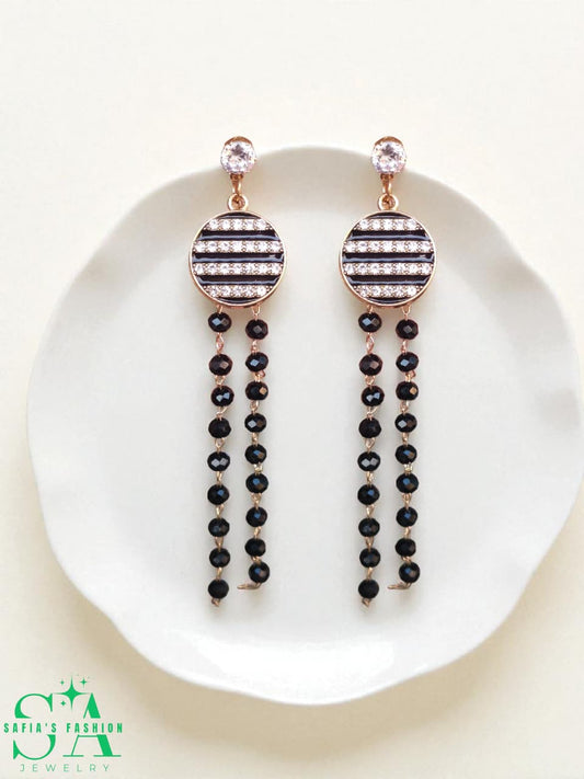 Pair of black beaded earrings with rose gold accents on a white plate, branded 'SA'.
Long Drop Earrings with Black Pearls – Elegant Jewelry for Women

Close-up of Black Pearl Drop Earrings – Stylish Party Wear

Woman Wearing Black Pearl Long Earrings – Fashion Jewelry