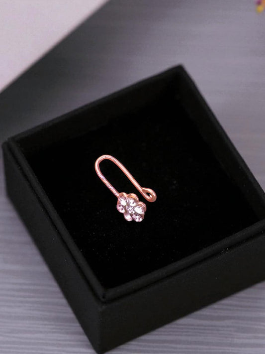 Rose gold earring with a clear gemstone in a black box on a gray surface