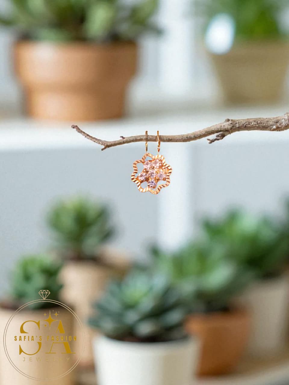 Rose gold floral earring hanging on a branch with blurred plants in the background