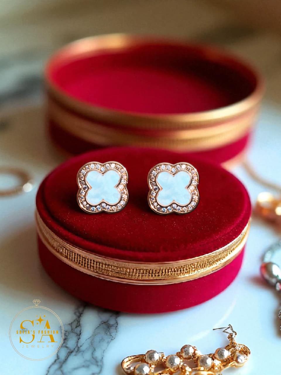 Pair of earrings on a red velvet stand with gold trim