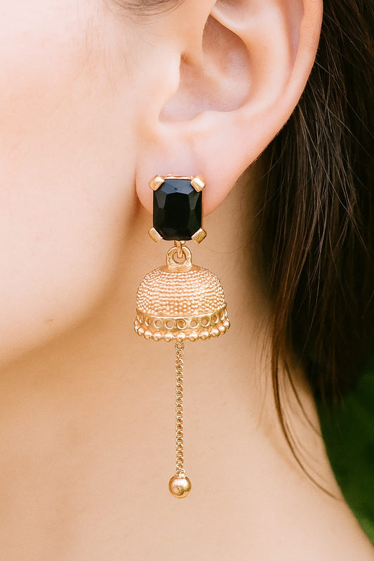 Gold earrings with a black gemstone worn by a person